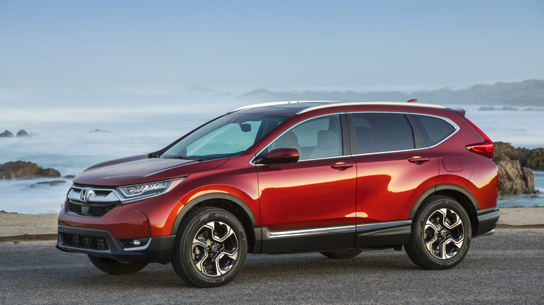 A red CR-V sits parked by the ocean.