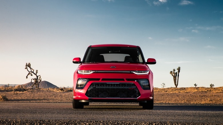 A red Kia Soul sits on a desert road.