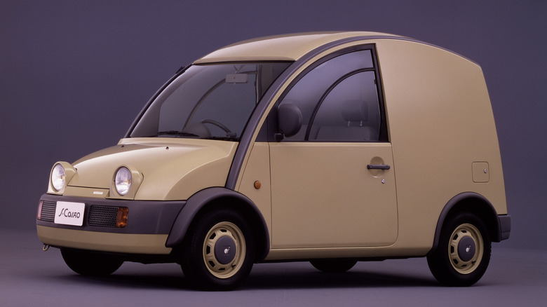 A factory studio portrait of a washed yellow Nissan S-Cargo retro van parked in a studio.