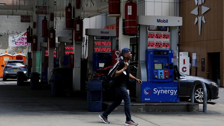 man walks near a gas station as gas prices are shown in a fuel dispenser on April 24, 2023 in New York City.