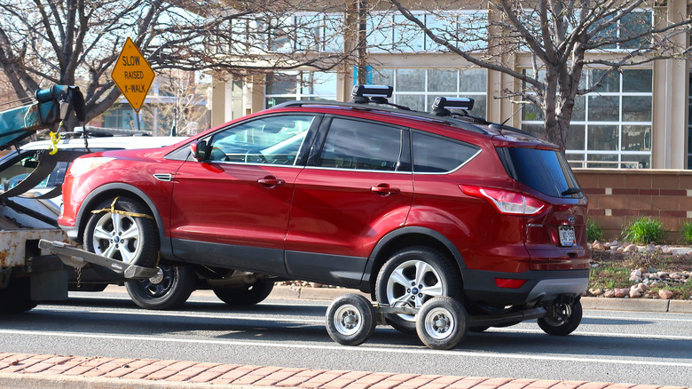 A red AWD car being towed with a tow dolly