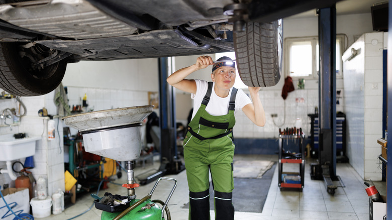 A technician inspects a car's undercarriage and wheels