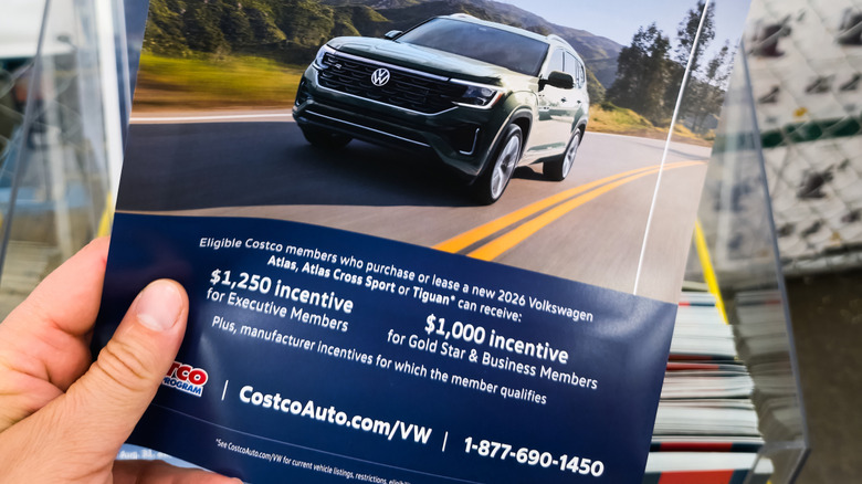 Close up of hand holding Costco flier for previous limited-time deals on Volkwagen SUVs