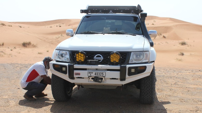 Driver deflating tires before driving on sand dunes