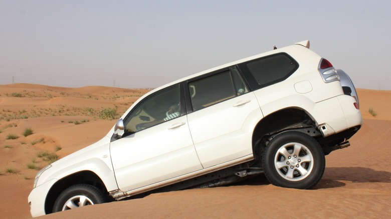 SUV driving on sand dunes with deflated tires