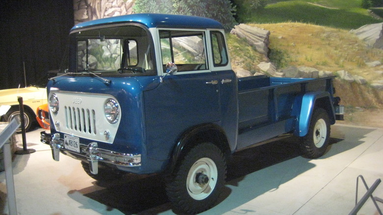 Blue Willys Jeep Forward Control FC pickup truck left front three-quarter view seen parked in a dispaly
