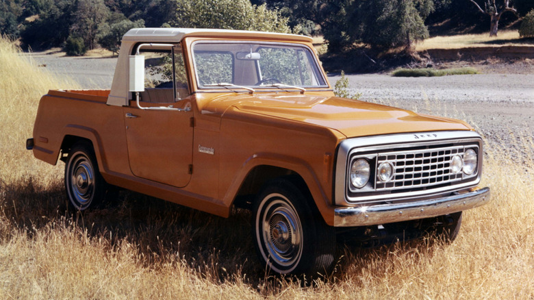 Orange 1972 Jeep Commando pickup right front three-quarter view parked on grass
