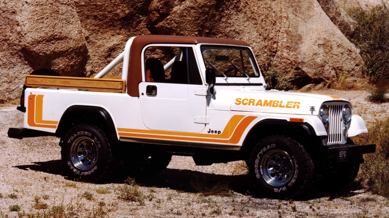 White 1982 Jeep CJ-8 Scrambler seen from left parked in front of rock cliffs