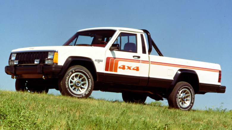 White 1986 Jeep Comanche pickup, left front three-quarter view seen parked on a grassy hillside