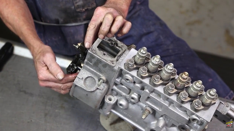 A mechanic's hands working on a P-pump fuel-injection system