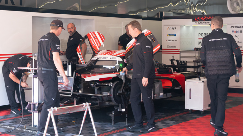 Porsche Penske Motorsport staff working on a Porsche 963 inside the team garage
