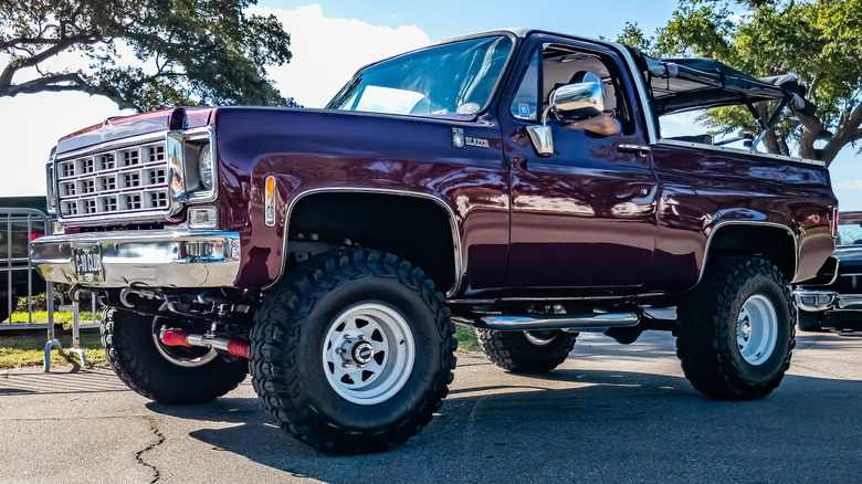 A burgundy colored 1980 Chevrolet Blazer parked at a car show.