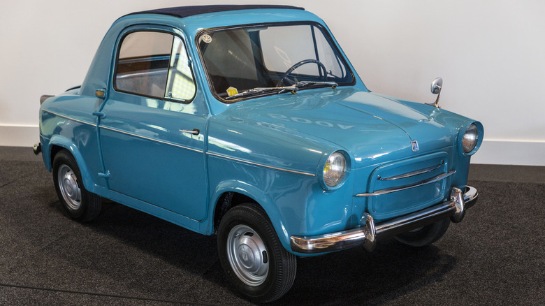 A blue vintage Vespa 400 on display at a car show.
