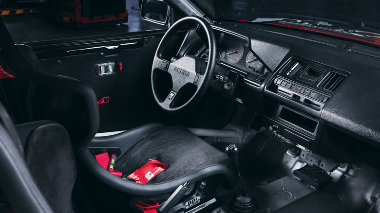 A look in through the passenger side at the Integra Racer's stock black dashboard and steering wheel as well as the racing seats