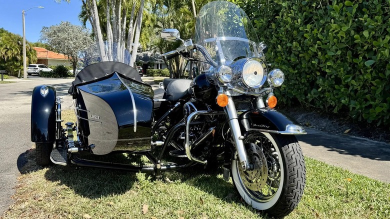 A 2005 Harley-Davidson Road King Classic with a Liberty sidecar parked on the grass on a sunny day.