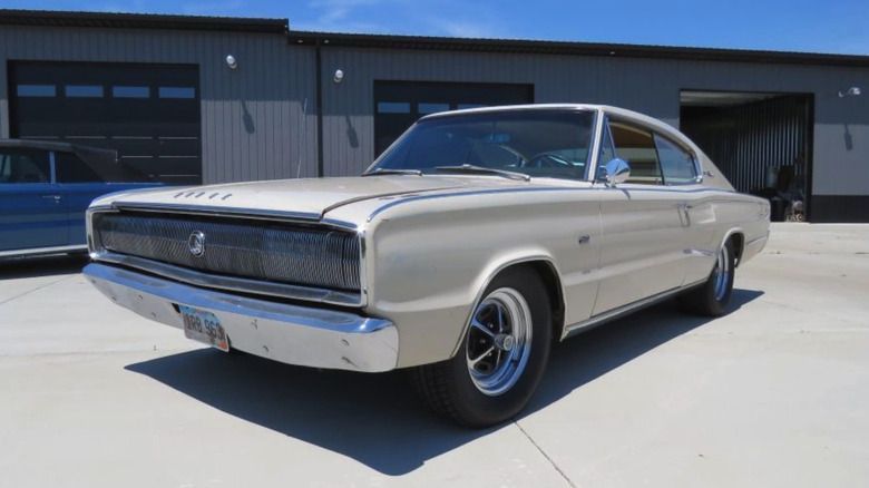 A white, 1966 Dodge 426 Hemi Charger parked on concrete in front of a large garage.