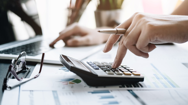 A close-up shot of a person using a calculator on a desk.