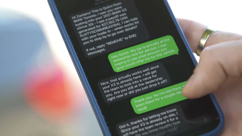 A phone displaying a conversation with an AI chatbot negotiating a trade-in offer