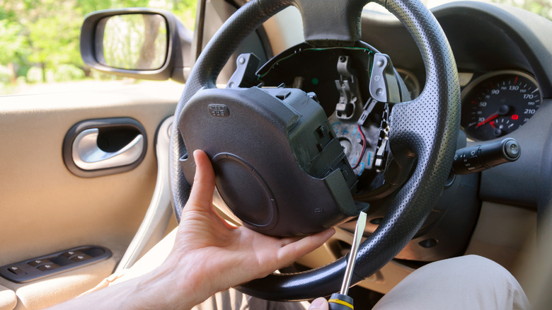 Removing an airbag from a steering wheel with a screwdriver