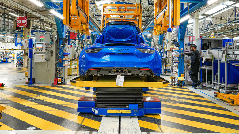 A rear shot of a blue Alpine A110R on the assembly line over yellow and black stripes