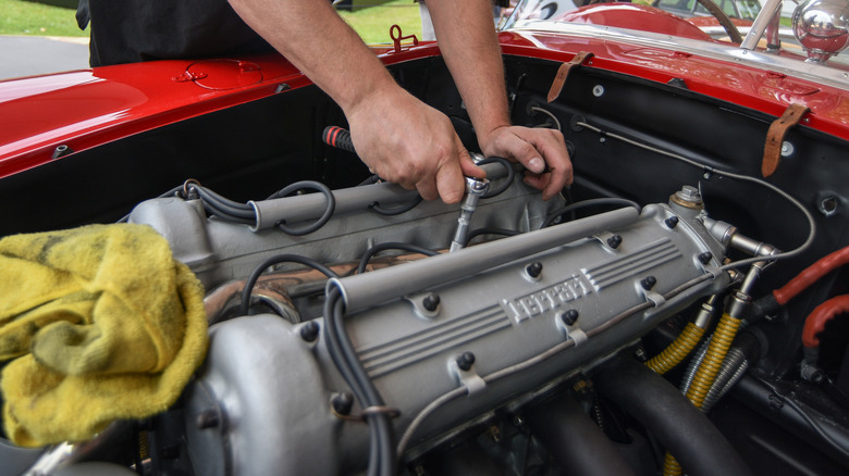 A Ferrari-Lampredi inline-4 engine in its engine bay, with two hands on it
