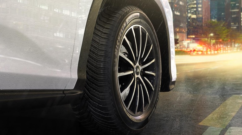 Michelin CrossClimate2 tire fitted to a white vehicle rolling on a wet urban road