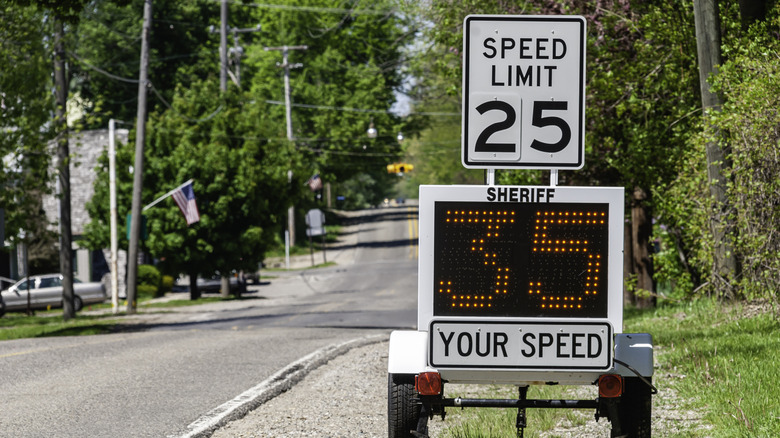 A sheriff/police speed limit roadside monitor with a posted speed limit sign and a digital readout of a car's actual speed lit below reading 10 mph over the posted speed limit.