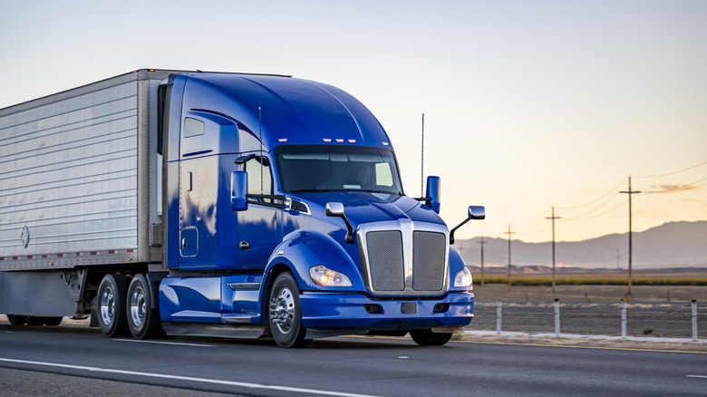 A blue Kenworth T680 driving down the road