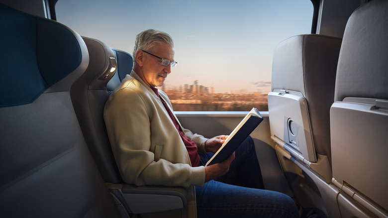An older man sits and reads using the personal reading light in the Amtrak NextGen Acela train.