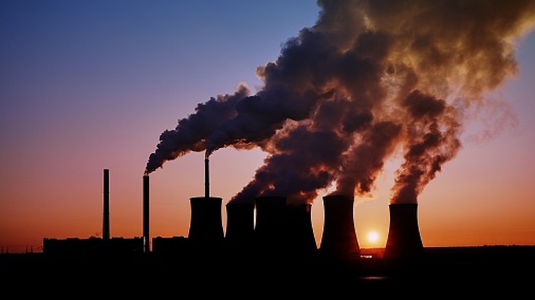 A coal power plant pollutes against the sunset
