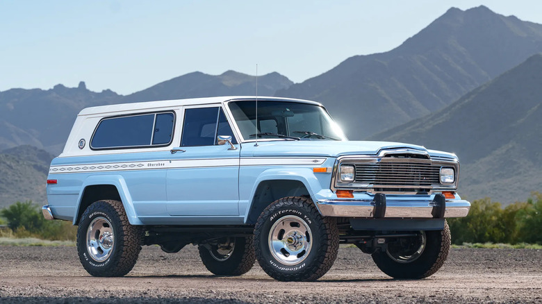A front three-quarters shot of the Cherokee parked on gravel in front of shrubs and arid mountains