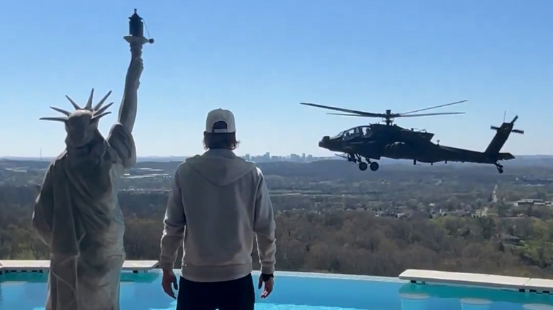 An AH-64 Apache helicopter hovering near Kid Rock at his Nashville mansion