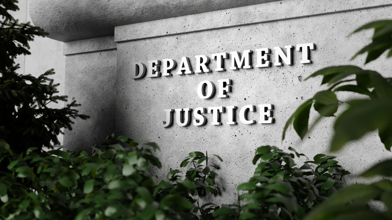 Department of Justice sign surrounded by green plants