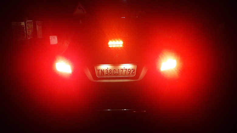 A rear view of a car in the dark with illuminated brake lights and a third brake light