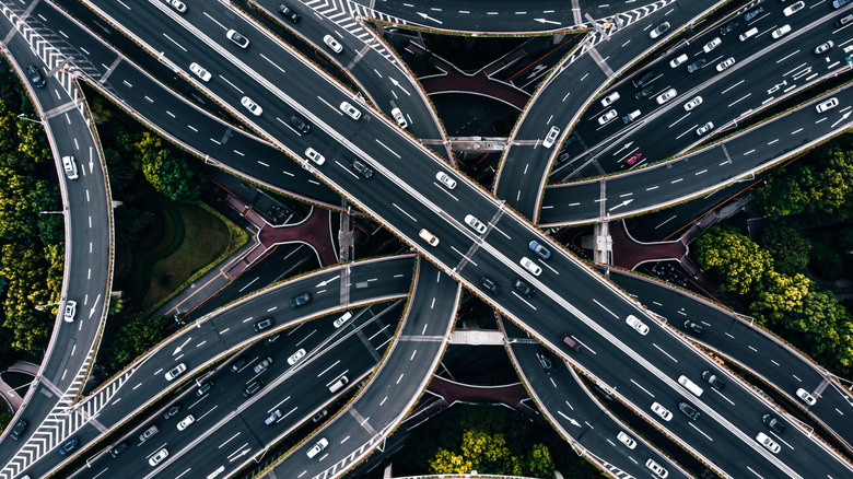 An aerial view of cars driving on a cloverleaf highway and entrance/exit ramps