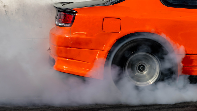 An orange car doing a smoky burnout