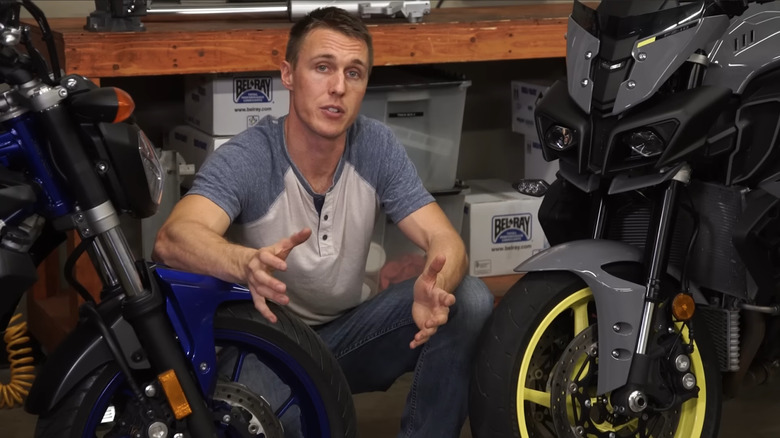 A man comparing a bike with inverted forks with a bike with conventional forks, placed side by side