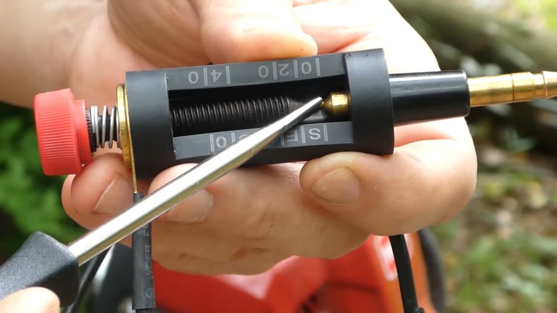 A hand holding an adjustable gap spark plug tester