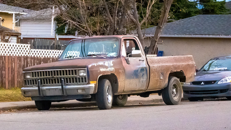 Rusty truck street parked next to the curb with its wheels turned