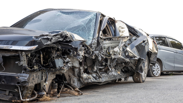 The aftermath of a car accident showing two very smashed-up vehicles.