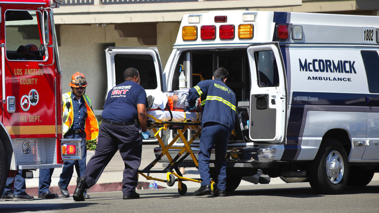A fire engine and ambulance crew load an accident victim into an ambulance.