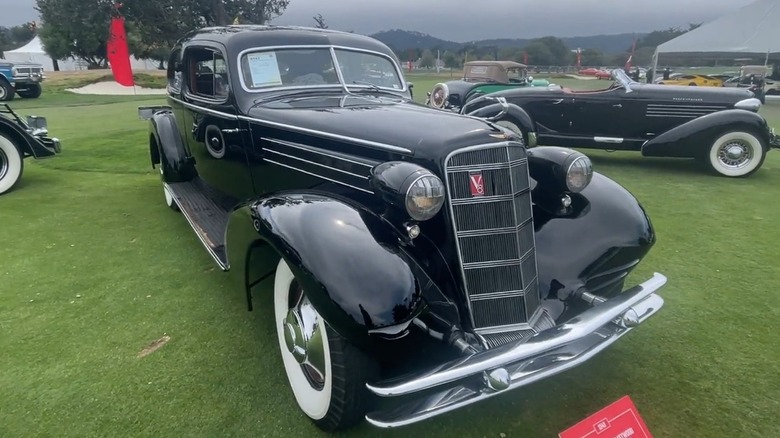 A black 1934 Cadillac Fleetwood Aerodynamic Coupe parked on grass at a Mecum Auctions sale