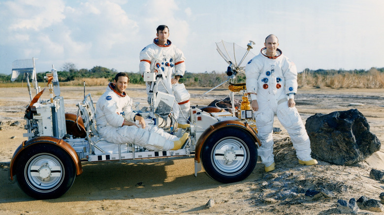 Charlie Duke (left), John Young, and Ken Mattingly pose with a training version of the lunar roving vehicle in a field at the Kennedy Space Center simulated to represent the lunar surface.
