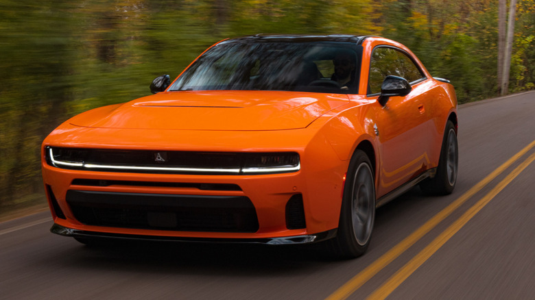 An orange 2026 Dodge Charger Scat Pack driving through a forest.