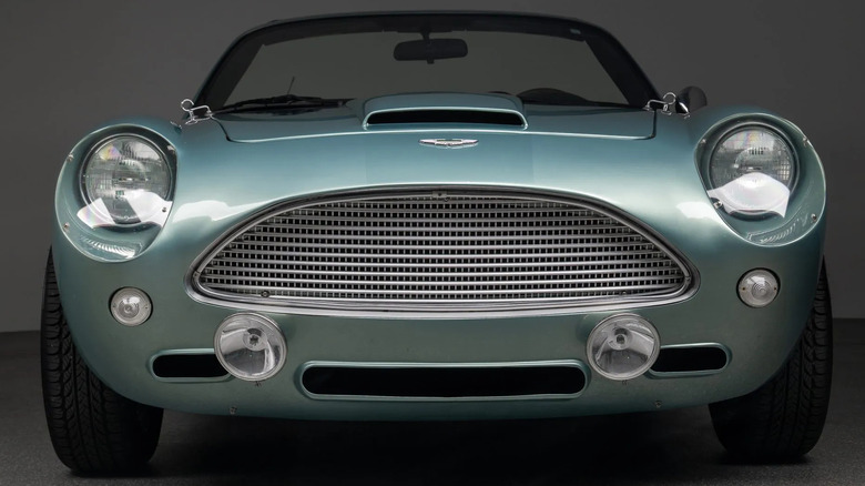 A close-up, head-on shot of the light green Miata-in-Aston's-Clothing in a studio in front of a gray background