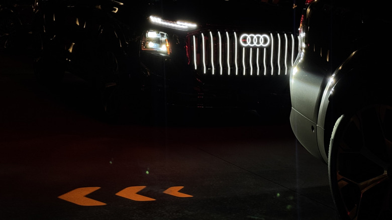 a photo of the projected turn signal in front of a Q9 with its headlights and grille illuminated at night time