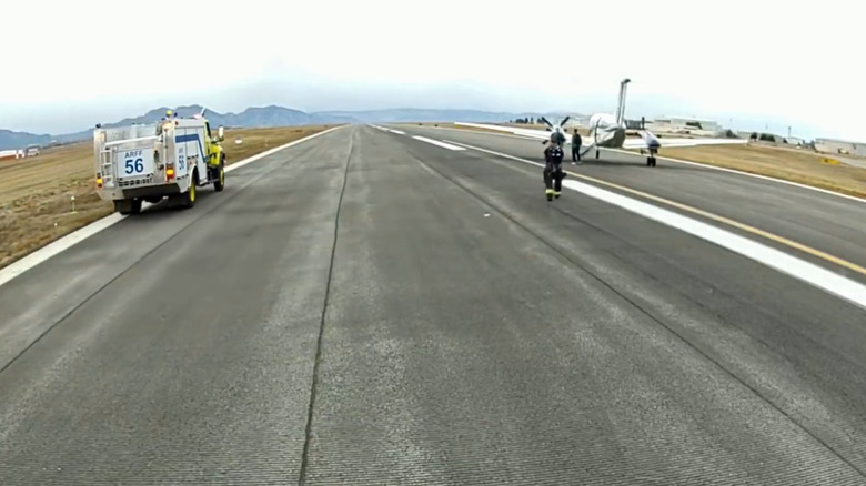 Firefighters approaching the Beechcraft Super King Air after landing at Rocky Mountain Metropolitan Airport.