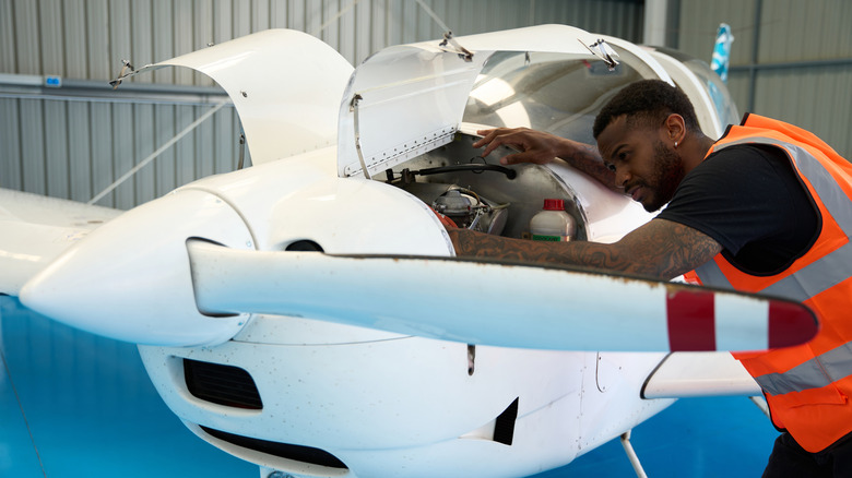 A young mechanic works on a small, single-engine piston airplane