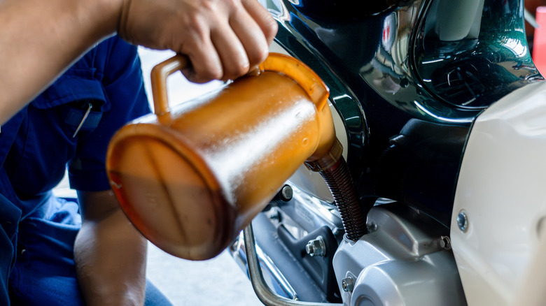 Mechanic pouring fresh oil into a motorcycle engine