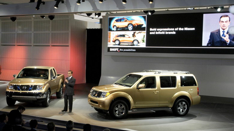 DETROIT - JANUARY 5: Nissan President and CEO Carlos Ghosn talks to the news media about the new 2005 Frontier pickup truck (L) and Pathfinder sport utility vehicle (R) at the North American International Auto Show January 5, 2004 in Detroit, Michigan. The show, which will feature more than 700 vehicles, opens to the public January 10. (Photo by Bryan Mitchell/Getty Images)